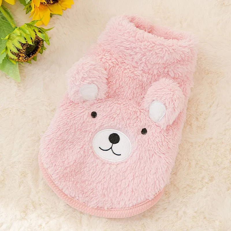 The Dog Face Cute Bear Dog Fur Coat in pink, displayed on a fluffy surface.