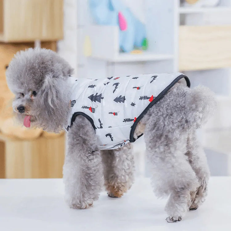 Side view of a poodle wearing a white dog snow suit with red and black winter patterns