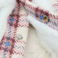Inside view of the white fleece fabric of a plaid dog coat, showing the stitching and button details