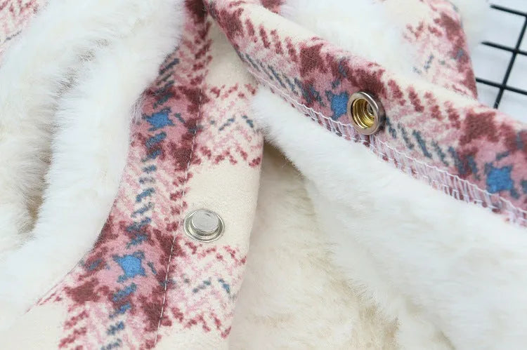 Inside view of the white fleece fabric of a plaid dog coat, showing the stitching and button details