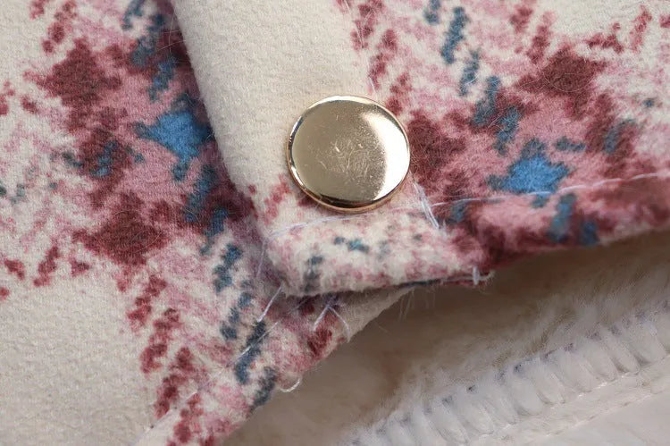 Close-up of the snap button detail on a pink plaid dog coat with white fleece lining