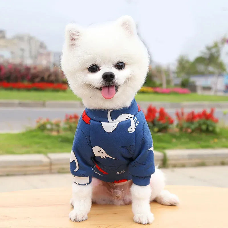 Adorable white dog wearing a Designer Dog Coat with colorful animal prints, showcasing a fashionable and cute appearance.