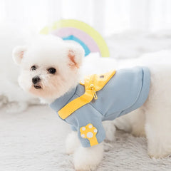 "Side view of a small white dog in a light blue sweater with a yellow bear-shaped satchel, showcasing Designer Dog Sweaters."